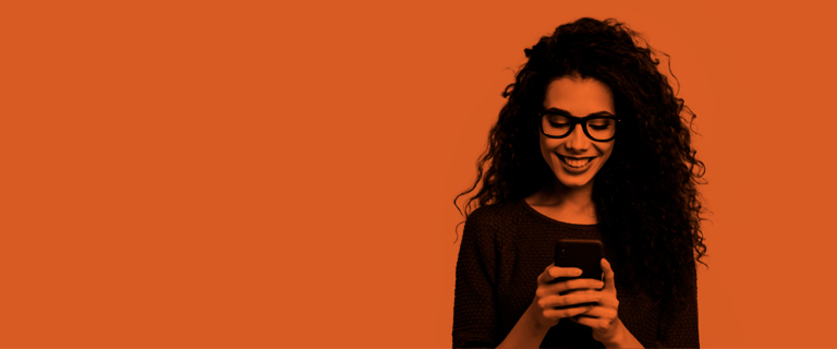 Mujer crespa sonriendo con el celular en las manos