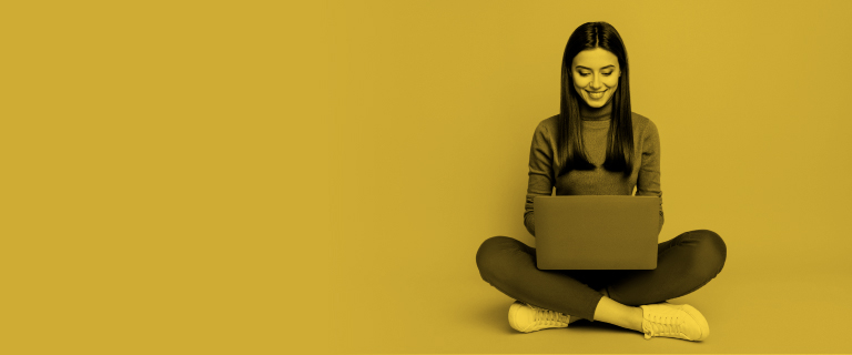 Mujer alegre sentada en el piso viendo su computadora