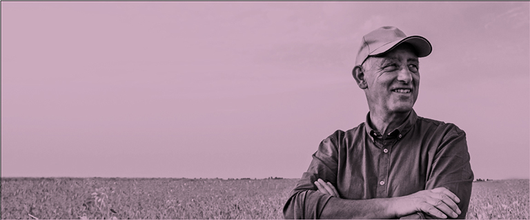 Adulto mayor con los brazos cruzados en un pastizal