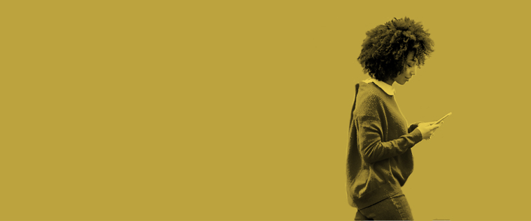 Mujer afro camina mientras ve su celular