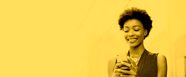 Mujer afro sonriendo utilizando celular