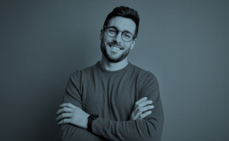 Hombre joven con barba y gafas alegre cruzando los brazos