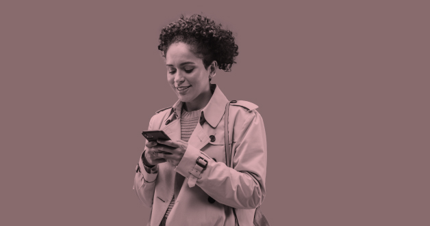 Mujer joven afro lee el celular en sus manos sonriendo